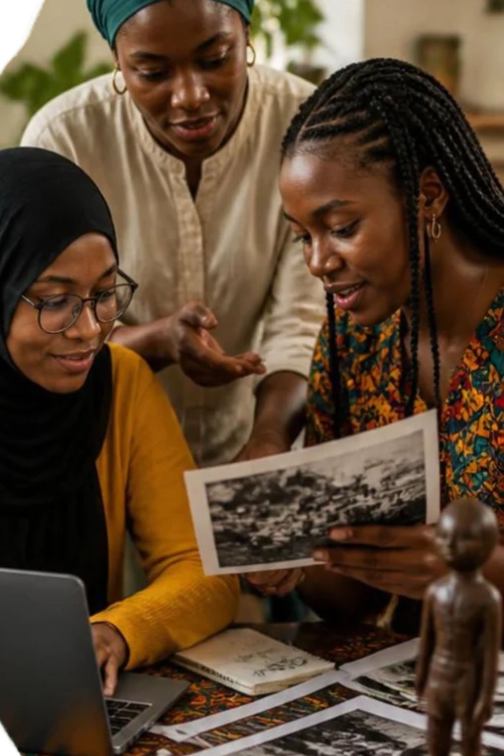 Women exploring heritage photographs together with a laptop and cultural objects