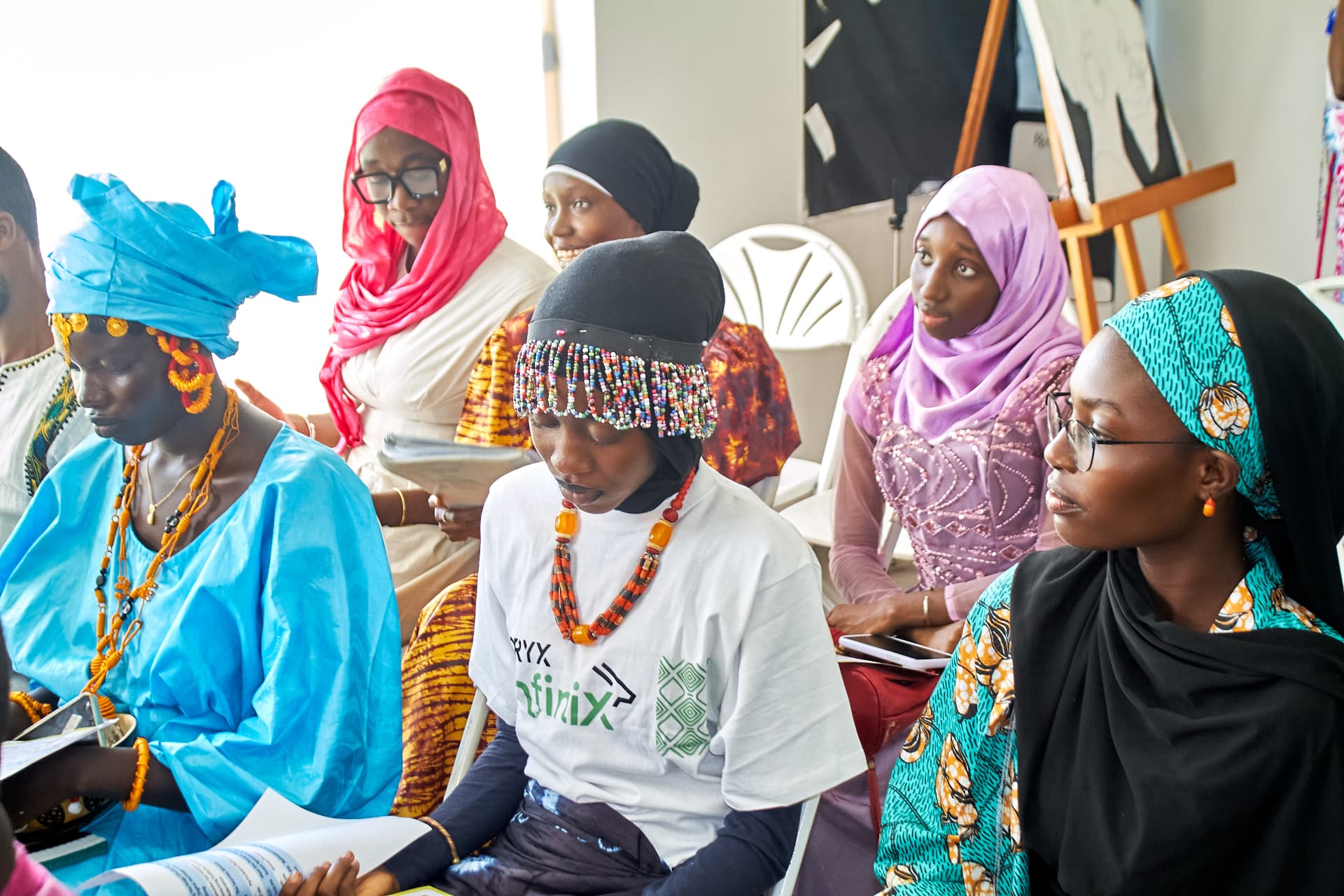 Women in colourful clothing listening and taking notes during the HERitage Connect session